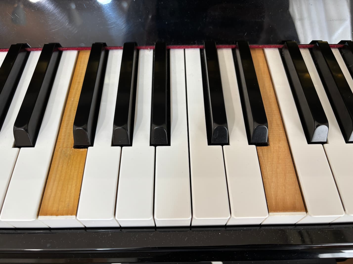 YAMAHAのアップライトピアノYC1SGの鍵盤が剥がれている状態の画像。修理作業の解説のために提示している。
